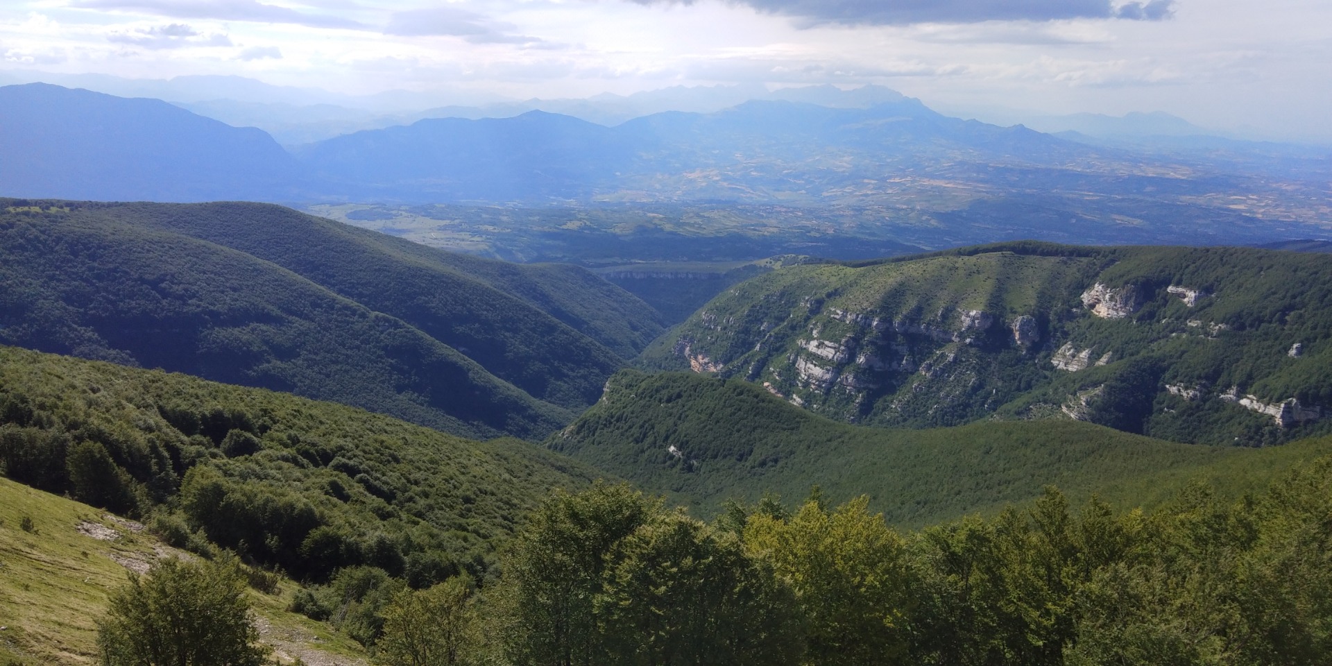 Vista panoramica sulla Majella con montagne verdi e vette coperte da nuvole all'orizzonte