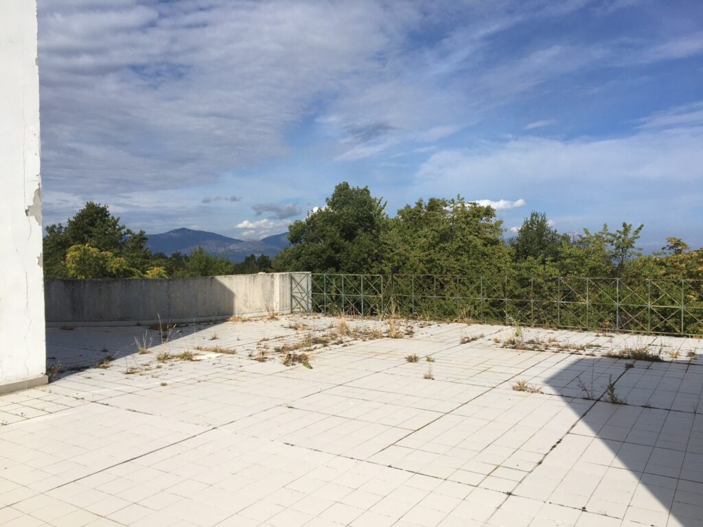 Terrazza dell'ecolodge con pavimento dissestato ed erbacce